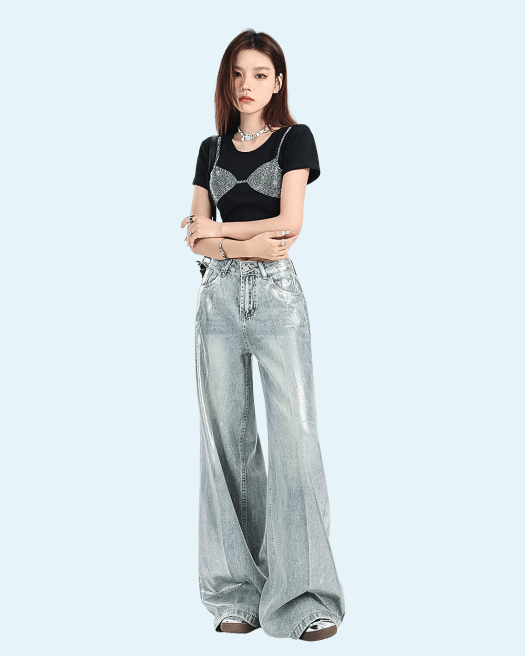 Fată tânără purtând pantaloni argintii strălucitori largi cu talie înaltă și tricou negru casual