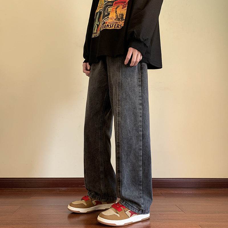 Pantaloni drepți vintage prespălați. Model purtând denim gri închis cu croială dreaptă largă, lungi peste gleznă