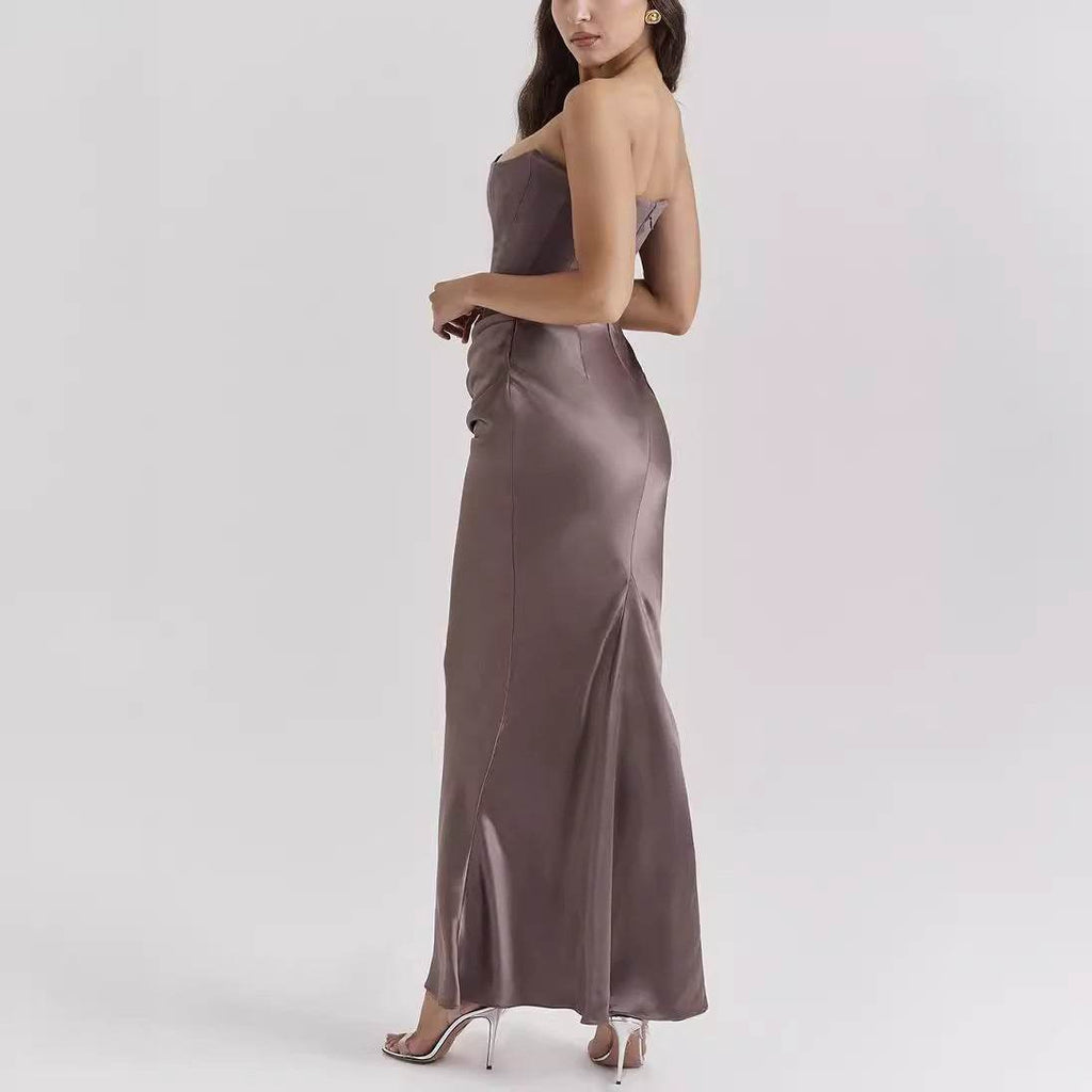 Rochie elegantă lungă cu umerii goi din satin taupe, croială mulată, model purtat lateral cu sandale cu toc