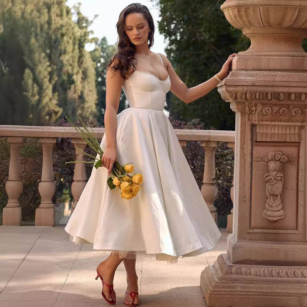 Rochie midi din satin alb cu corset si fusta evazata, purtata pe terasa, accesorizata cu trandafiri galbeni