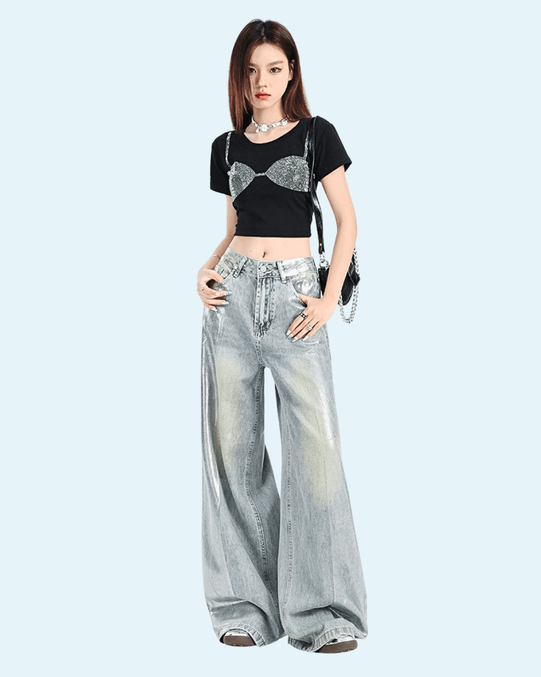 Femeie purtând pantaloni argintii strălucitori largi și bluza neagră scurtă cu imprimeu argintiu