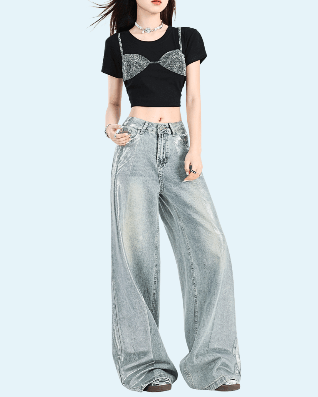 Pantaloni argintii strălucitori largi și lejeri purtați de femeie cu tricou negru și accesoriu argintiu