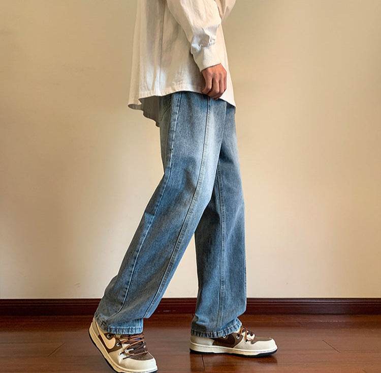 Model purtând Pantaloni drepți vintage prespălați din denim deschis la culoare asortați cu tricou alb oversized și pantofi sport