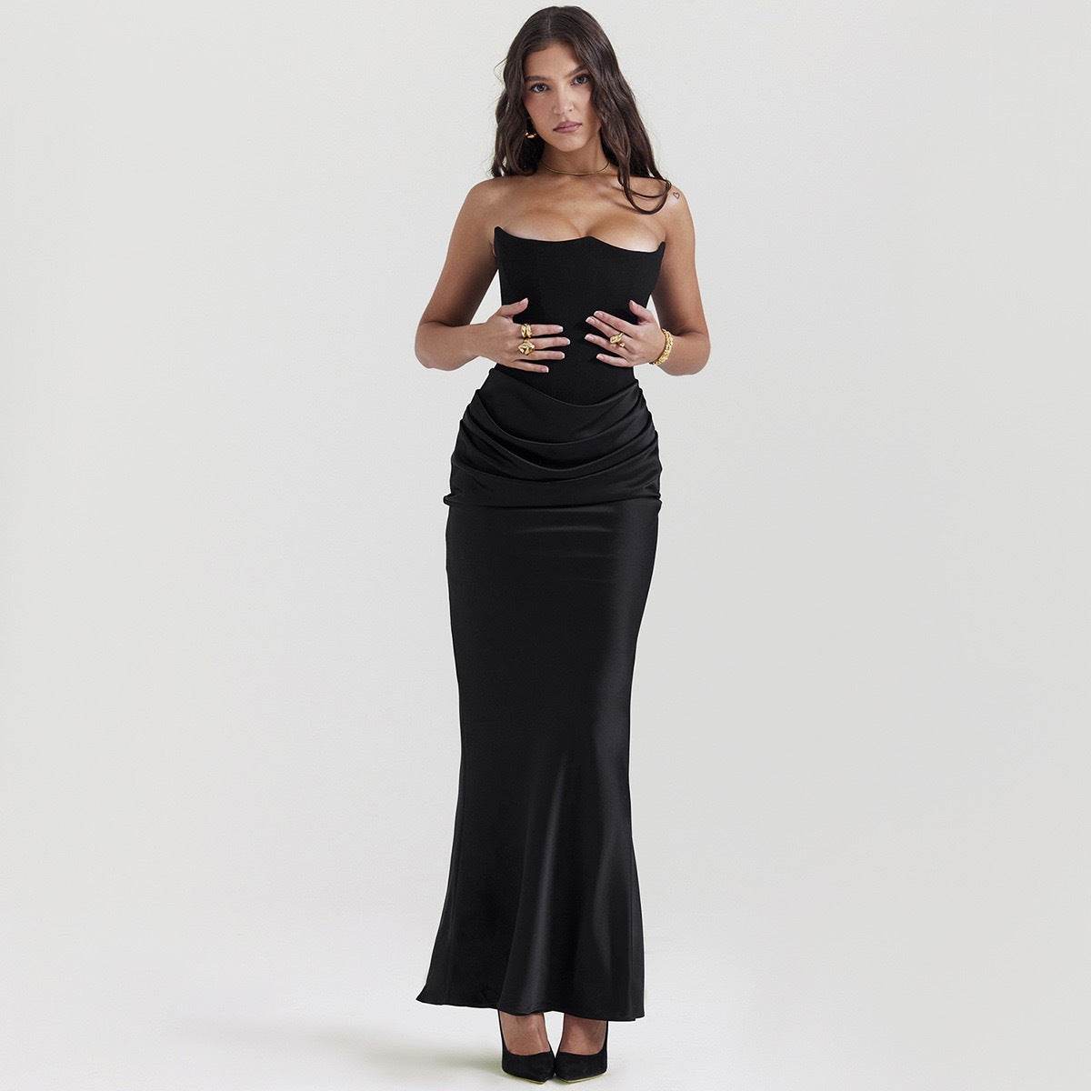 Rochie elegantă lungă cu umerii goi neagră mulată cu talie drapată și tiv până la podea purtată de model