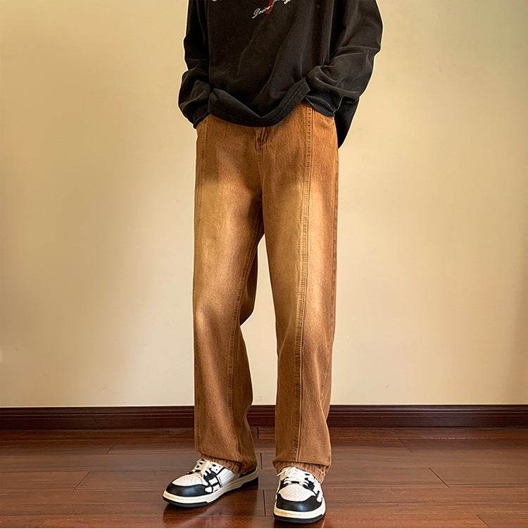 Pantaloni drepți vintage prespălați maro deschis purtați cu hanorac negru oversized si pantofi sport pe podea din lemn