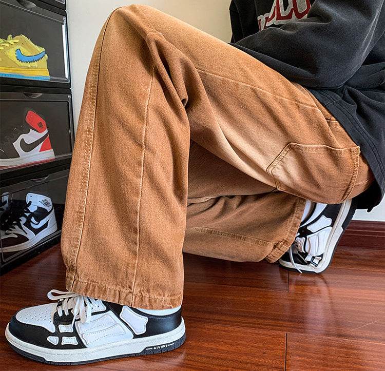 Pantaloni drepți vintage prespălați. Bărbat șezând cu pantaloni maro caramiziu largi și adidași albi și negri