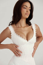 Rochie scurtă casual albă cu corset și bretele din dantelă model mulat femeie cu mâinile în talie