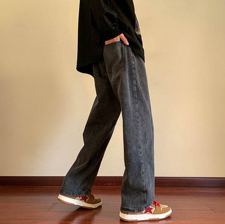Pantaloni drepți vintage prespălați din denim gri închis purtați lateral cu buzunare, croială relaxed și teniși casual