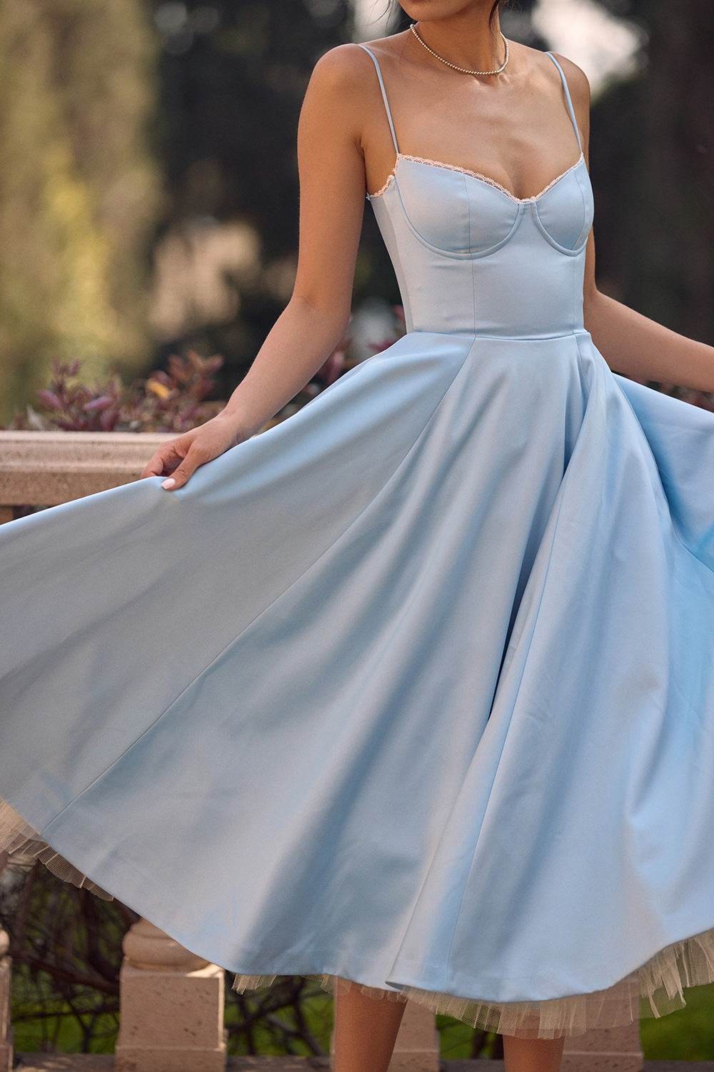 Rochie midi din satin albastru deschis cu bretele subtiri corset conturat si fusta evazata purtata outdoor