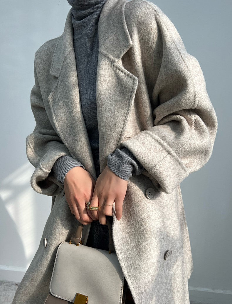 Adele Double Wool Coat in soft beige, styled over a gray turtleneck for a chic layering look