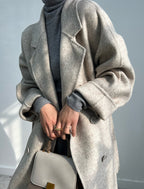 Adele Double Wool Coat in soft beige, styled over a gray turtleneck for a chic layering look