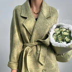 Adele Double Wool Coat in light green with a belted waist, stylishly worn over a black top