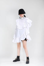 Model wearing an Asymmetric Dress with Ruffles in white, paired with black ankle boots