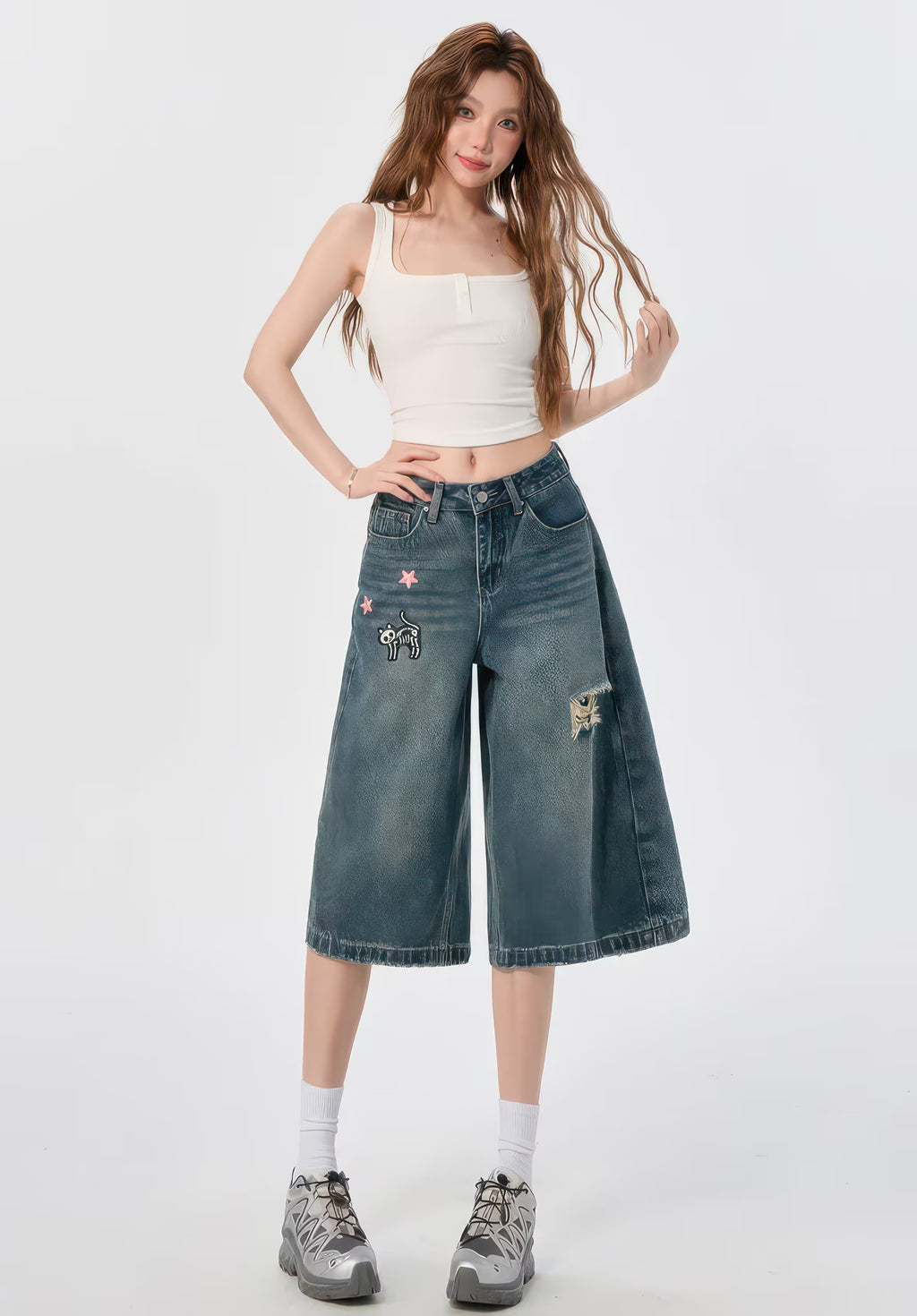Model purtând Blugi evazați "Funny Kitten" denim cu broderii, top alb scurt și adidași gri