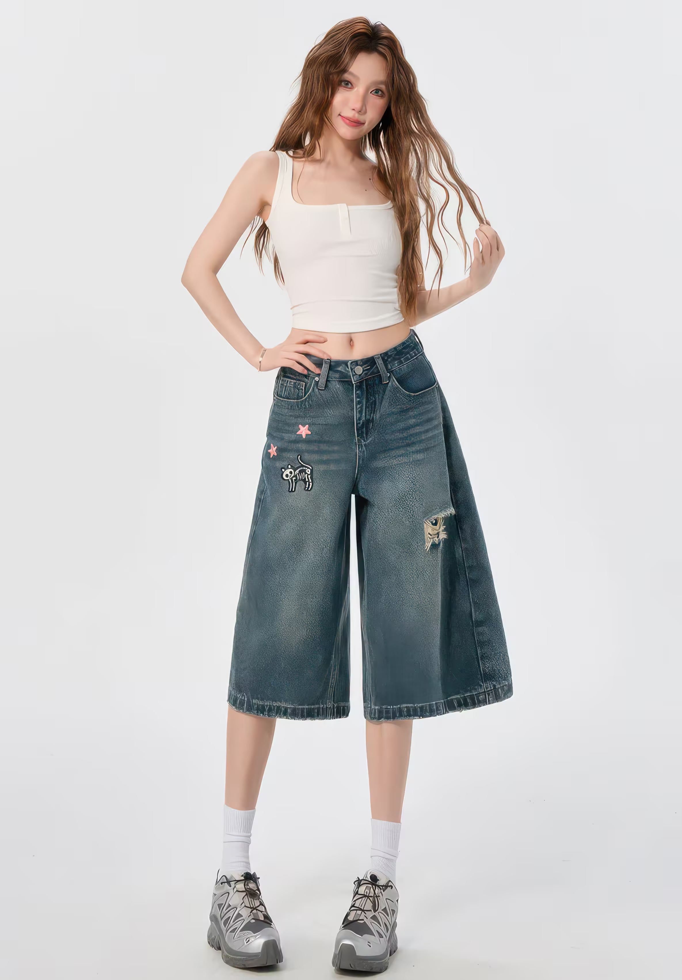 Model purtând Blugi evazați "Funny Kitten" denim cu broderii, top alb scurt și adidași gri