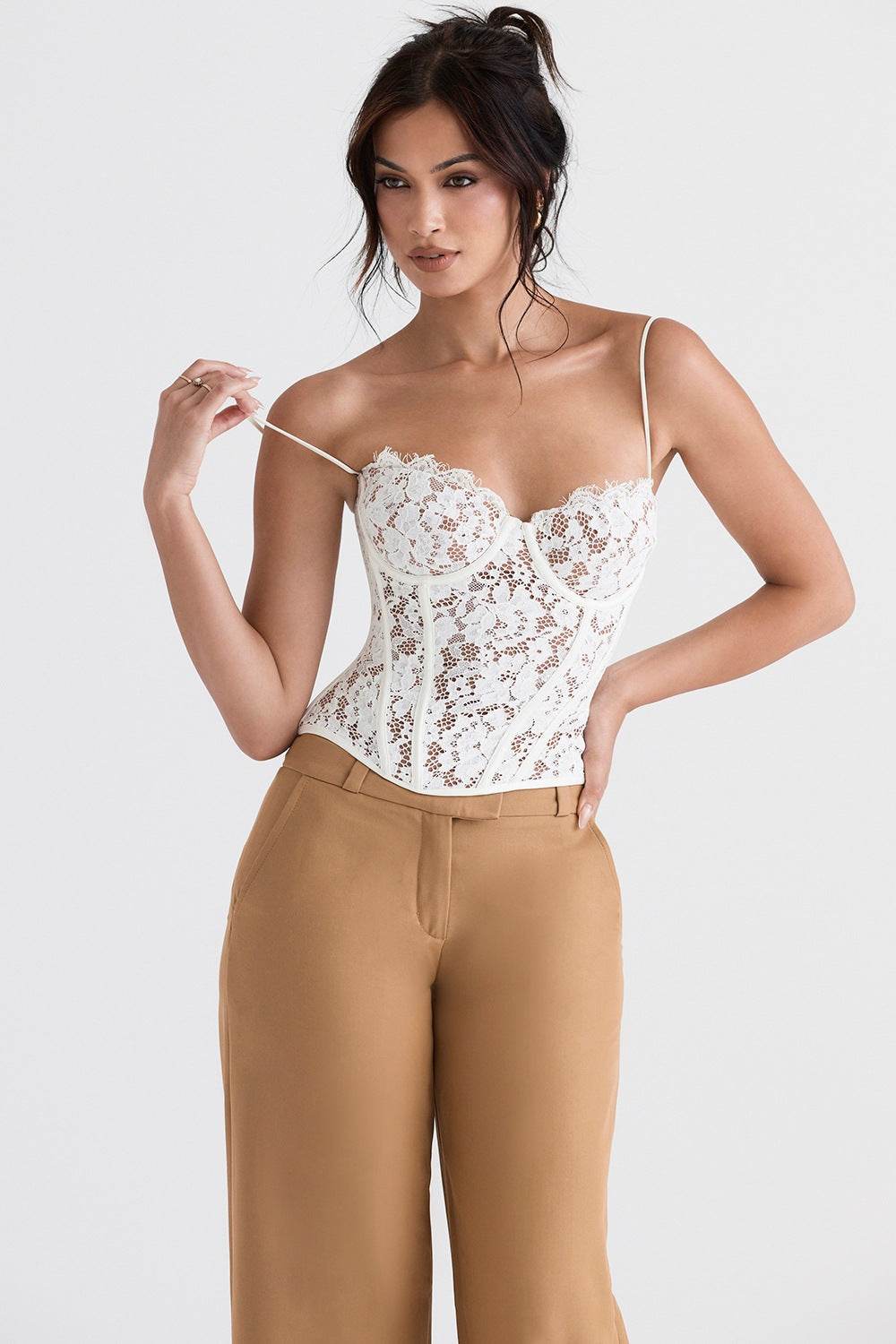Corset din dantelă alb cu bretele foarte subțiri și cupe conturate, model purtat cu pantaloni camel