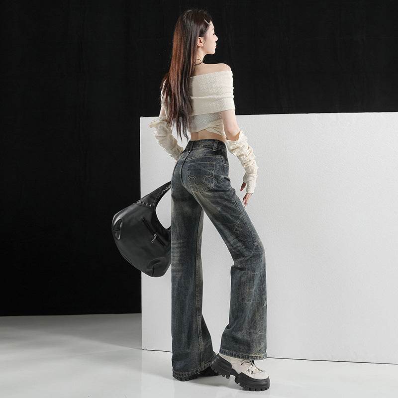 Model văzut din spate purtând Pantaloni evazați cu aer retro și uzură artistică. Top alb off shoulder și geantă neagră.
