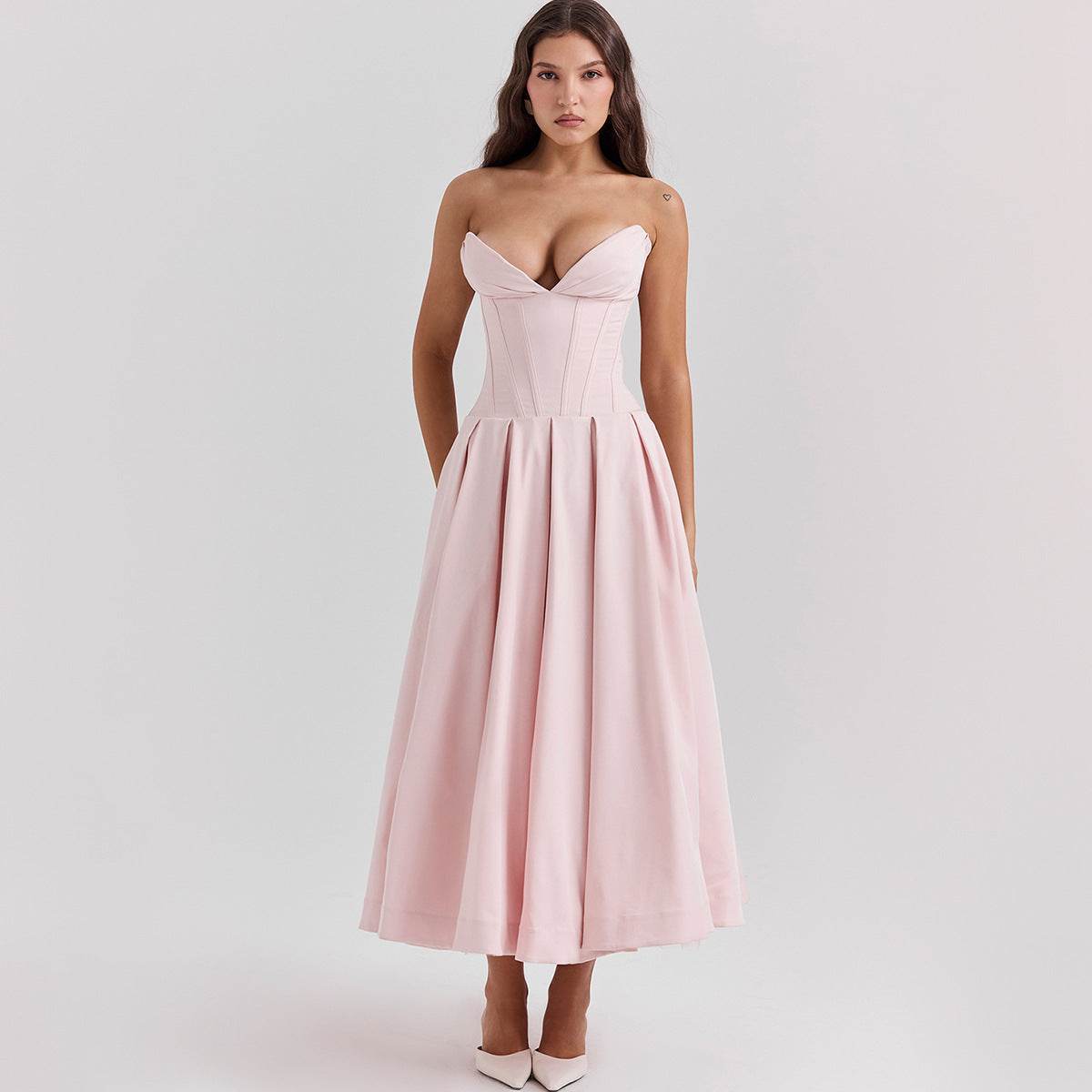 Rochie cu croială maxi și decolteu adânc. Rochie roz pal fără bretele cu corset structurat și fustă plisată midi
