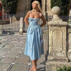 Rochie de vară lungă stil vintage. Model blond în curte poartă rochie bleu cu bretele subțiri, corset și fustă evazată midi