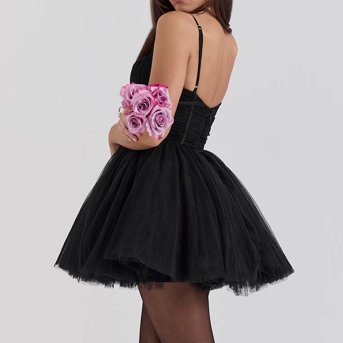 Rochie mini cloș neagră din tull cu bretele subțiri și spate decupat, fustă voluminoasă, ținând un buchet de trandafiri roz