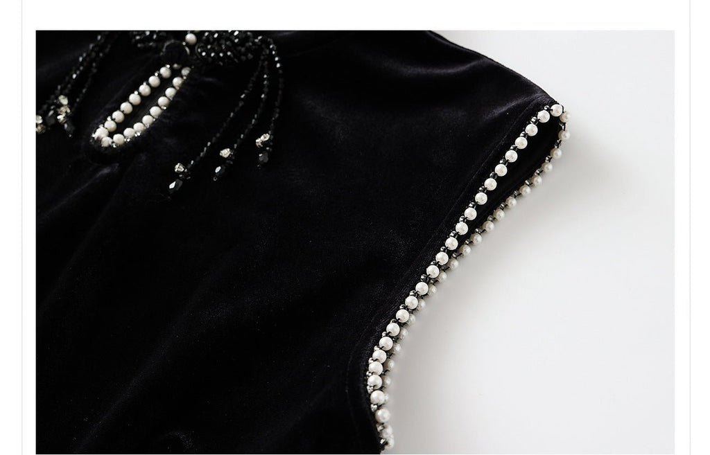 Close-up of a black velvet dress with beads highlighting intricate bead detailing on the neckline and sleeves