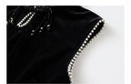 Close-up of a black velvet dress with beads highlighting intricate bead detailing on the neckline and sleeves
