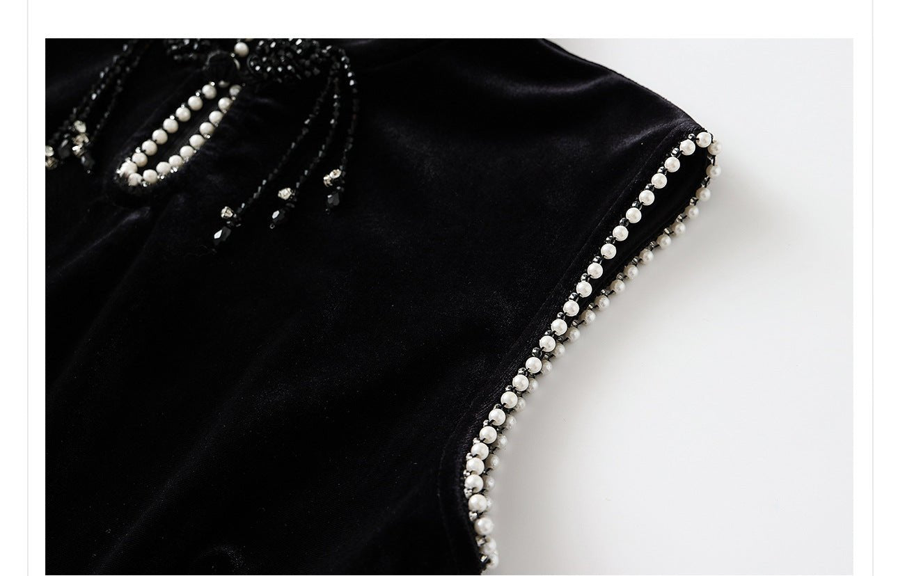 Close-up of a black velvet dress with beads highlighting intricate bead detailing on the neckline and sleeves