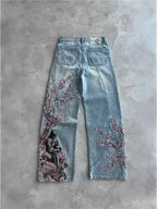 Bloom Drift Wide Leg Jeans featuring floral embroidery and a unique design on a light blue background