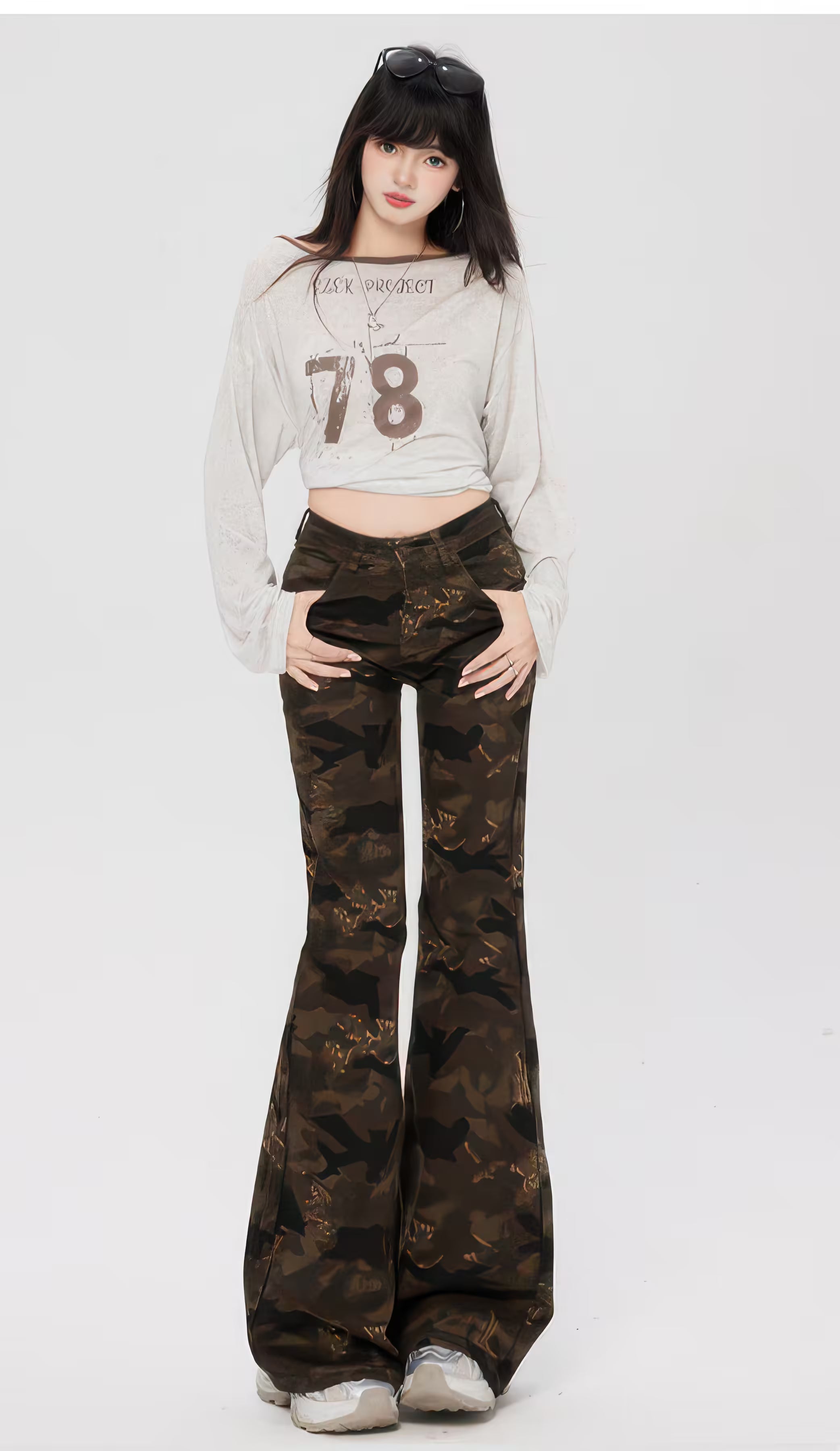 Model purtând Pantaloni "Camouflage Flare" cu talie înaltă, croială mulată pe coapse și evazare dramatică, imprimeu camuflaj.