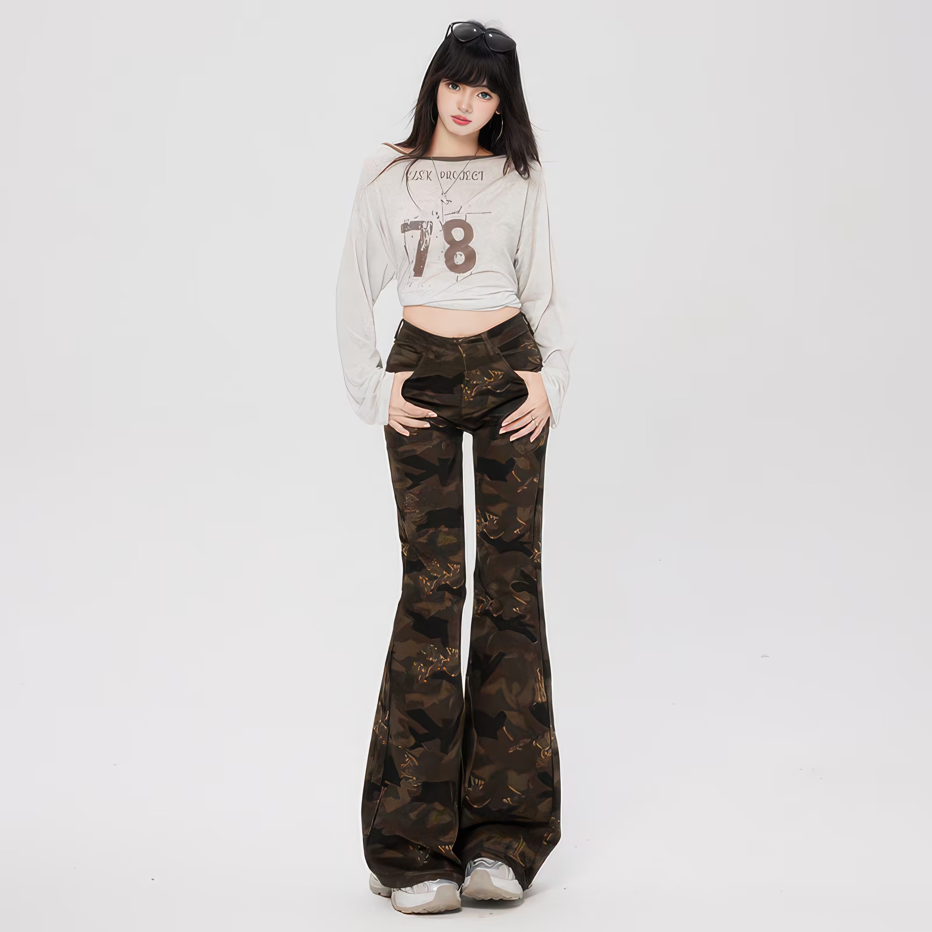 Model tânăr purtând Pantaloni "Camouflage Flare" din material camuflaj evazați, talie înaltă, pantofi sport.