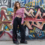 Model wearing Butterfly Black Tie Dye Wide Leg Denim Jeans with a cropped pink sweater against a graffiti background