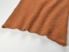 Close-up of warm, textured fabric showcasing the Camille Knit Dress Wool Elegance in a rich brown color