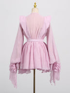 Elegant pink dress with asymmetric design and cut-out details featuring flowing sleeves and a cinched waist