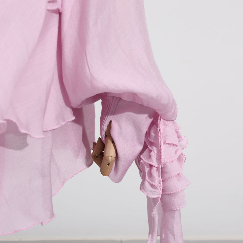 Light pink dress with asymmetric design and cut-out details showcasing flowing fabric and unique styling