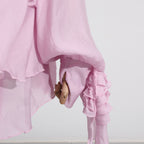 Light pink dress with asymmetric design and cut-out details showcasing flowing fabric and unique styling