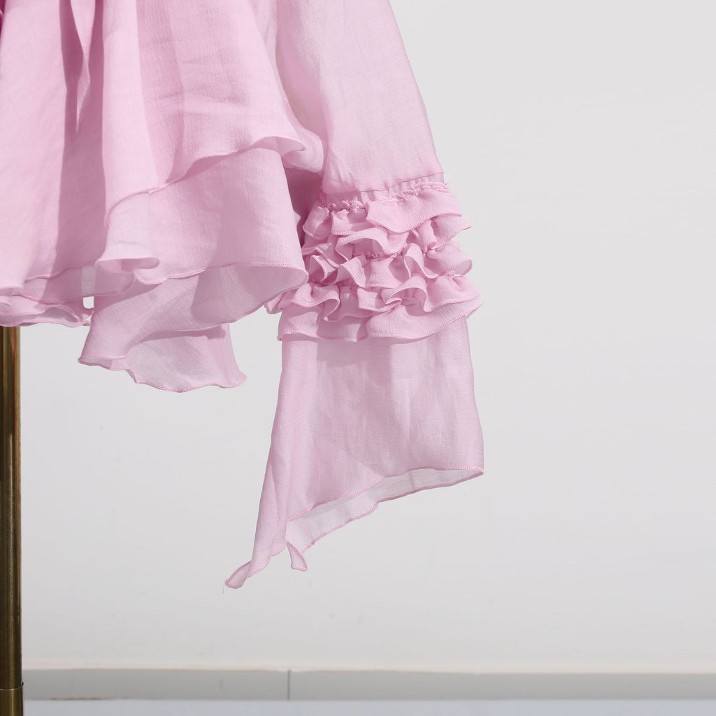 Pink dress with asymmetric design and cut-out details, featuring ruffled sleeves for a stylish look