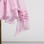 Pink dress with asymmetric design and cut-out details, featuring ruffled sleeves for a stylish look