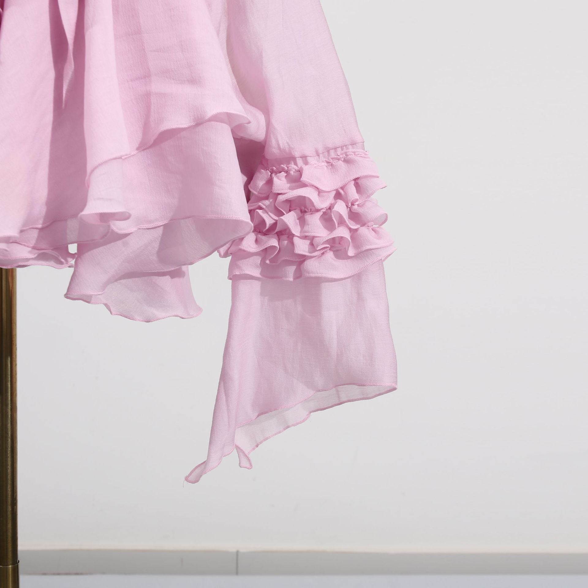 Pink dress with asymmetric design and cut-out details, featuring ruffled sleeves for a stylish look