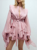 Elegant pink dress with asymmetric design and cut-out details featuring long sleeves and ruffled hem