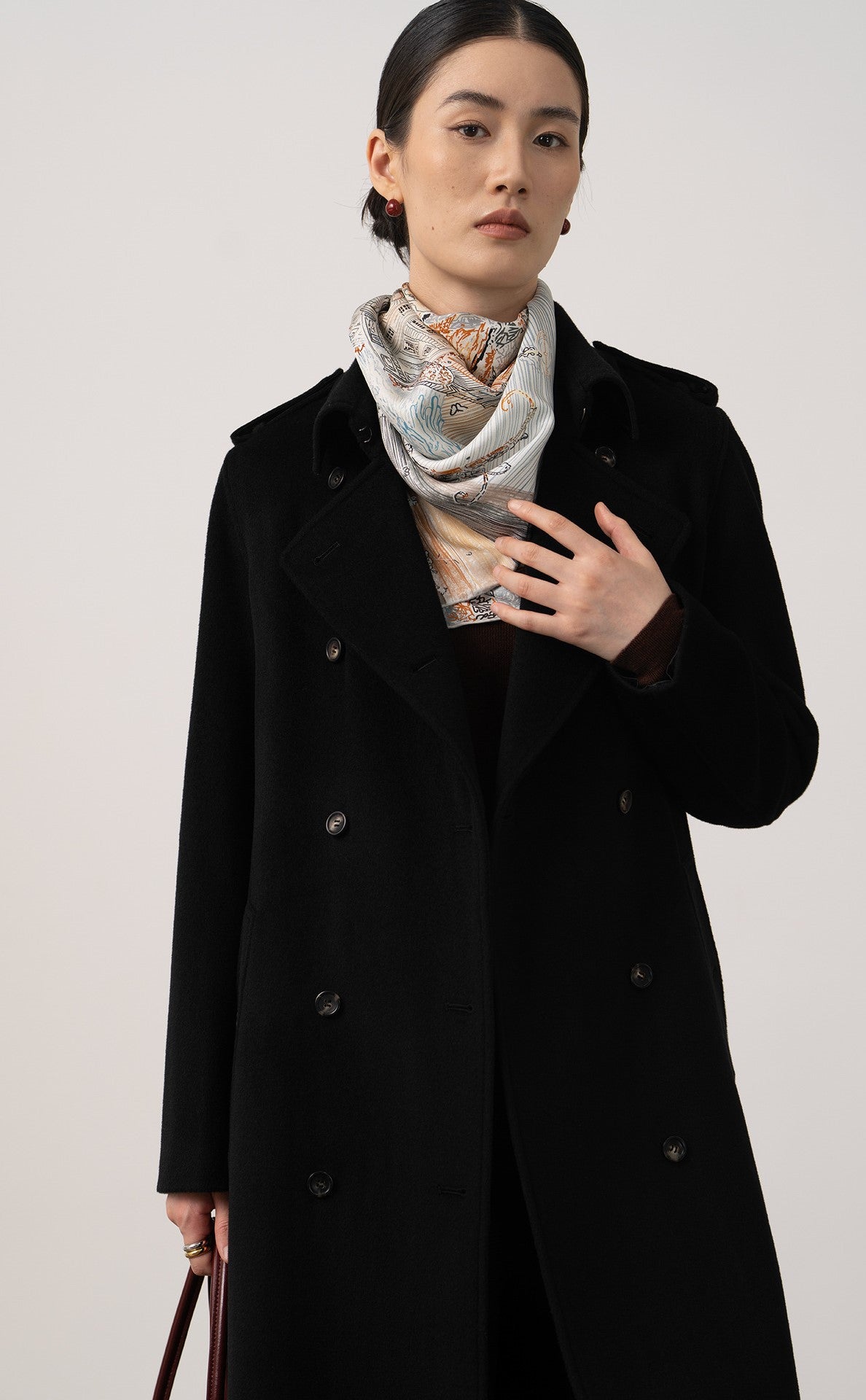 Elegant Elara Wool Coat Cashmere X Mulberry Silk in black, styled with a patterned scarf for a refined look.