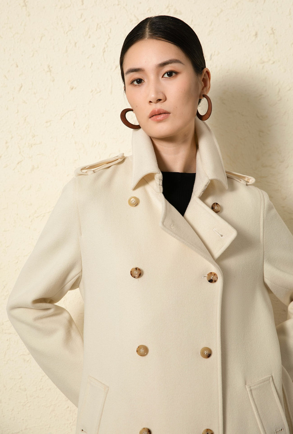 Fashion model wearing the Elara Wool Coat Cashmere X Mulberry Silk in cream color with stylish buttons