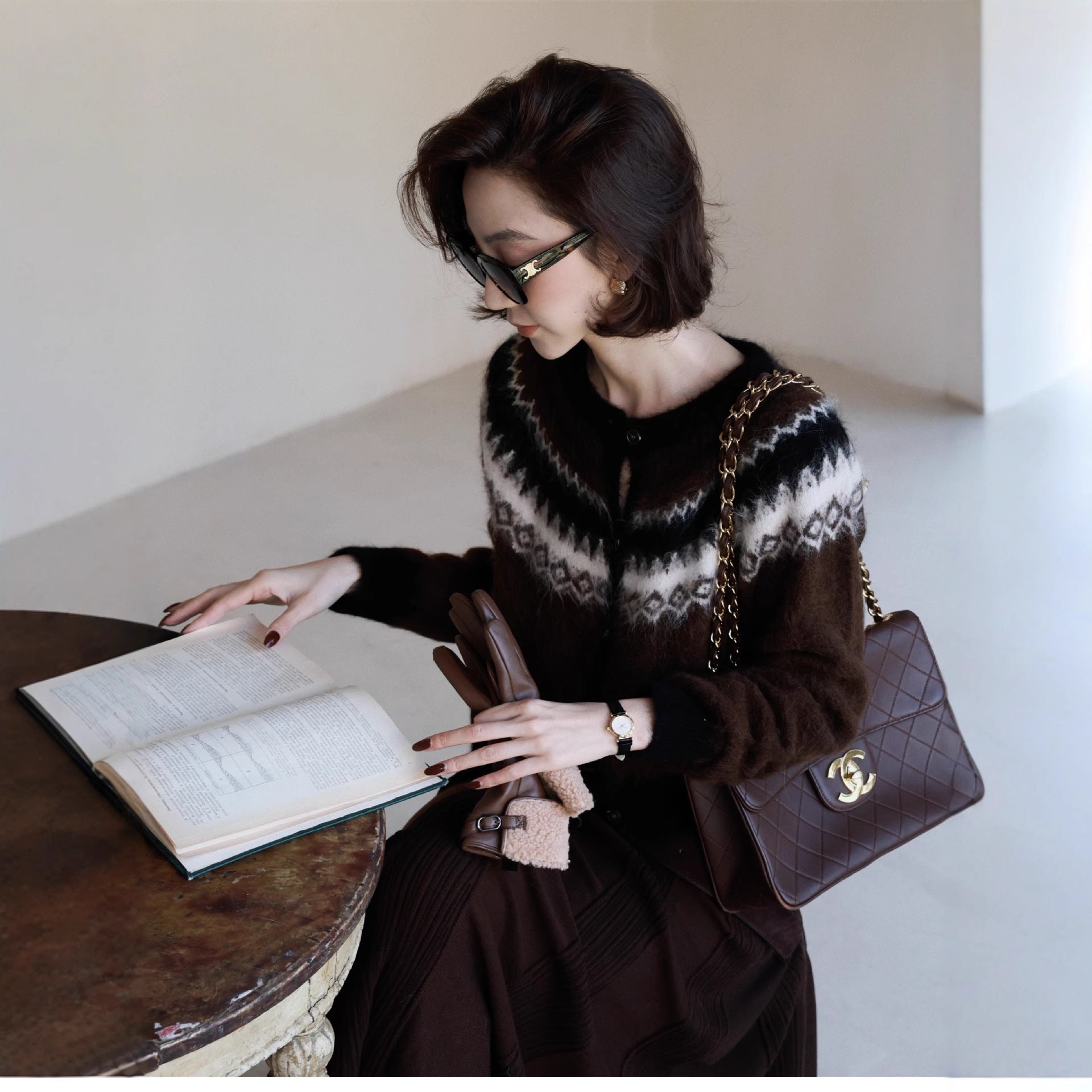 Woman reading a book while wearing a stylish Fair Isle Core Cardigan in a cozy indoor setting