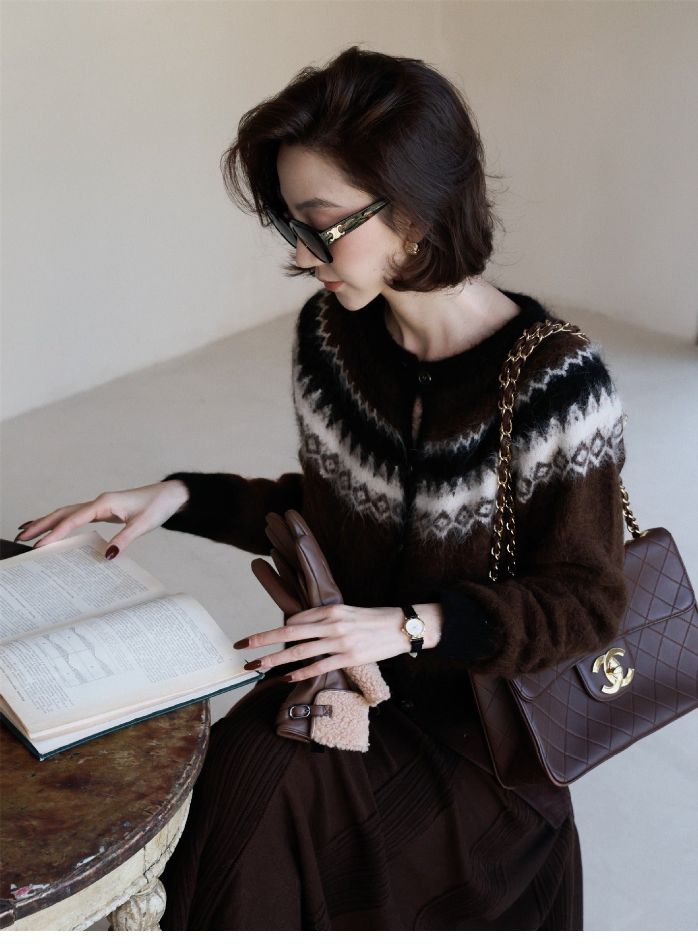 Woman reading a book while wearing a stylish Fair Isle Core Cardigan in brown and black patterns