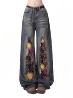 Firework Bloom Wide-Leg Denim Pants with colorful floral patterns on a vintage wash base