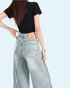 Back view of glossy effect pants in light denim with a relaxed fit and high-rise waist