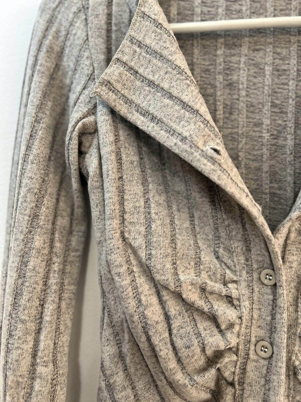 Close-up of a grey knitted cardigan with a collar and button detail, perfect for layering