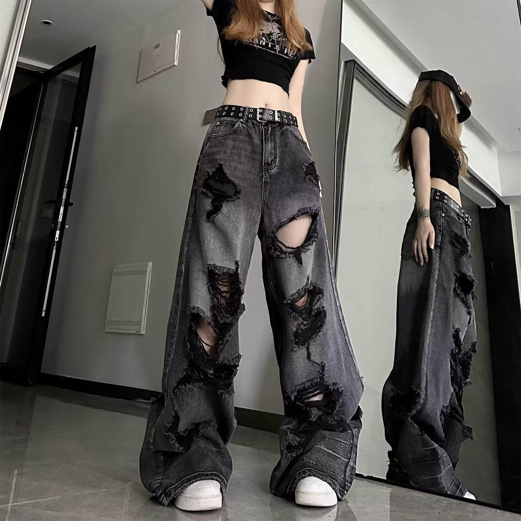 High waisted black ripped baggy jeans with large distressed holes worn with a black crop top and belt