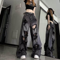 High waisted black ripped baggy jeans with large distressed holes worn with a black crop top and belt