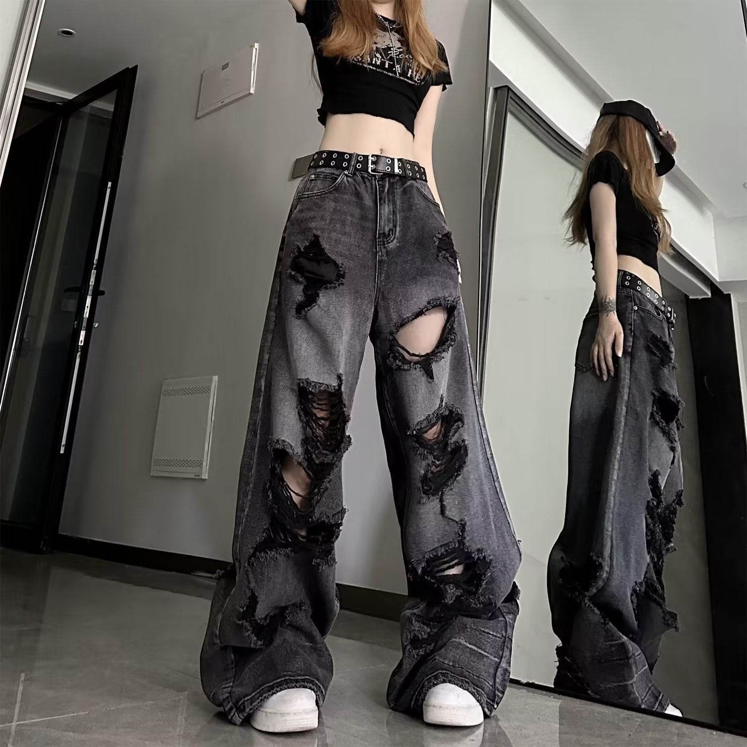 High waisted black ripped baggy jeans with large distressed holes worn with a black crop top and belt