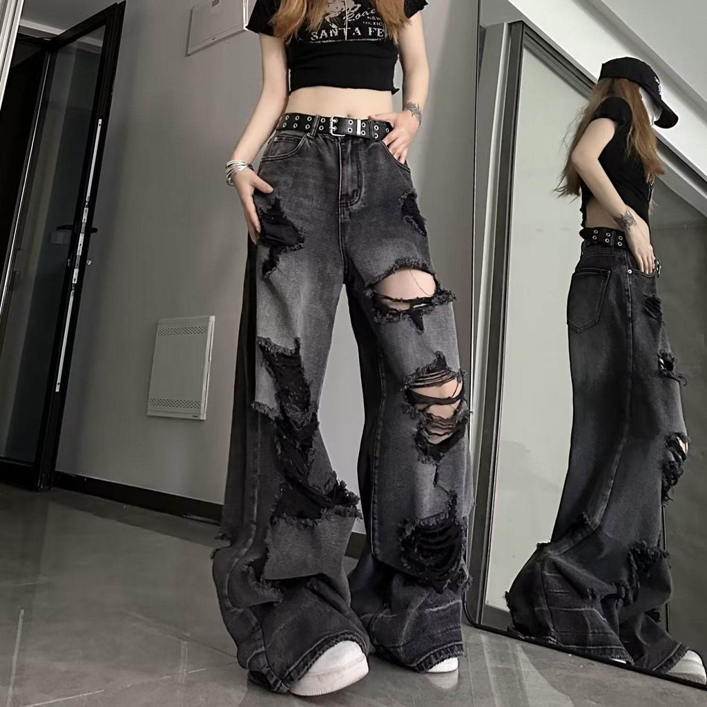 High waisted black ripped baggy jeans with distressed detailing worn by a model in a casual indoor setting